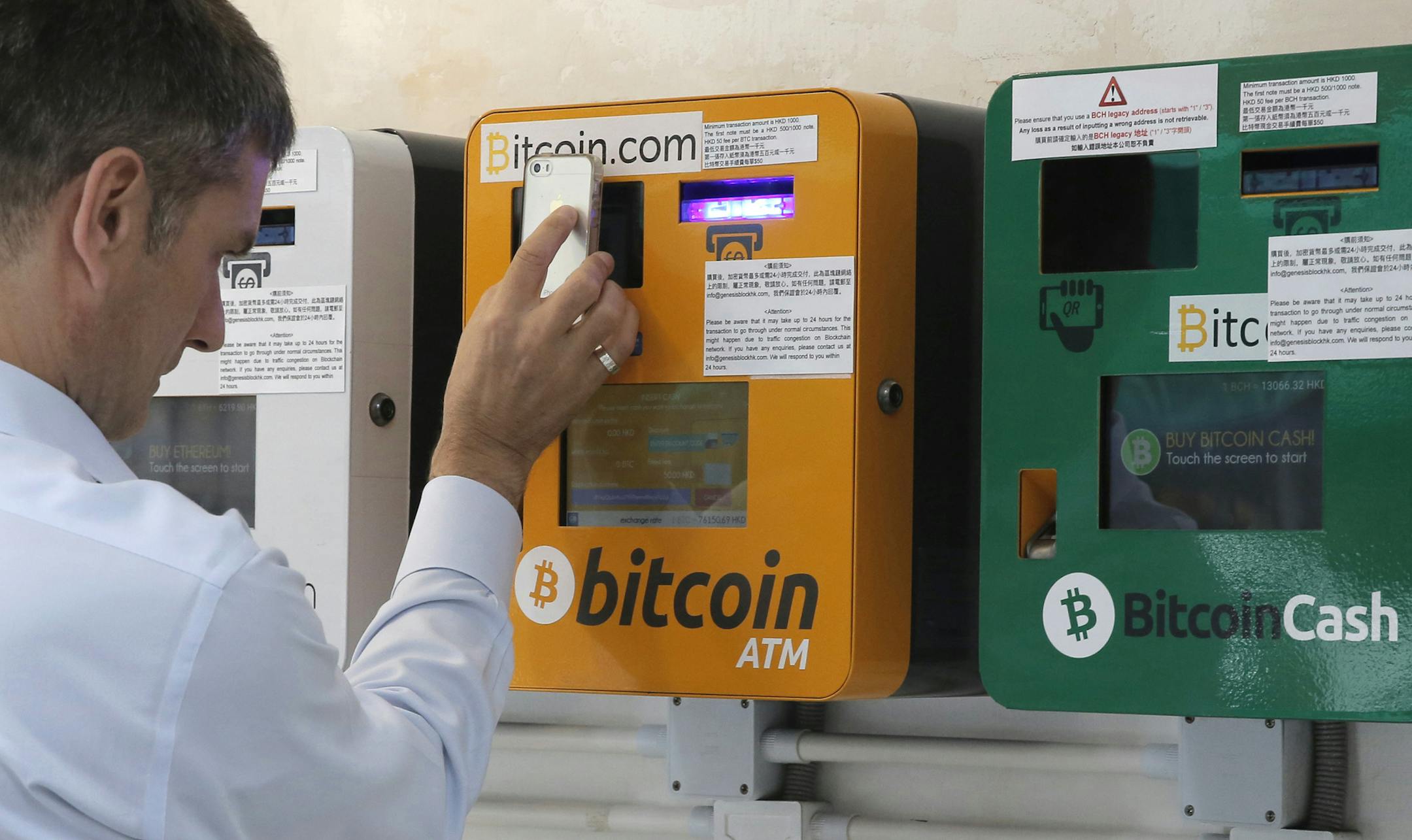 A man uses the Bitcoin ATM in Hong Kong, Friday, May 11, 2018. Bitcoin is the world's most popular virtual currency. Such currencies are not tied to a bank or government and allow users to spend money anonymously. (AP Photo/Kin Cheung) ORG XMIT: XKC106