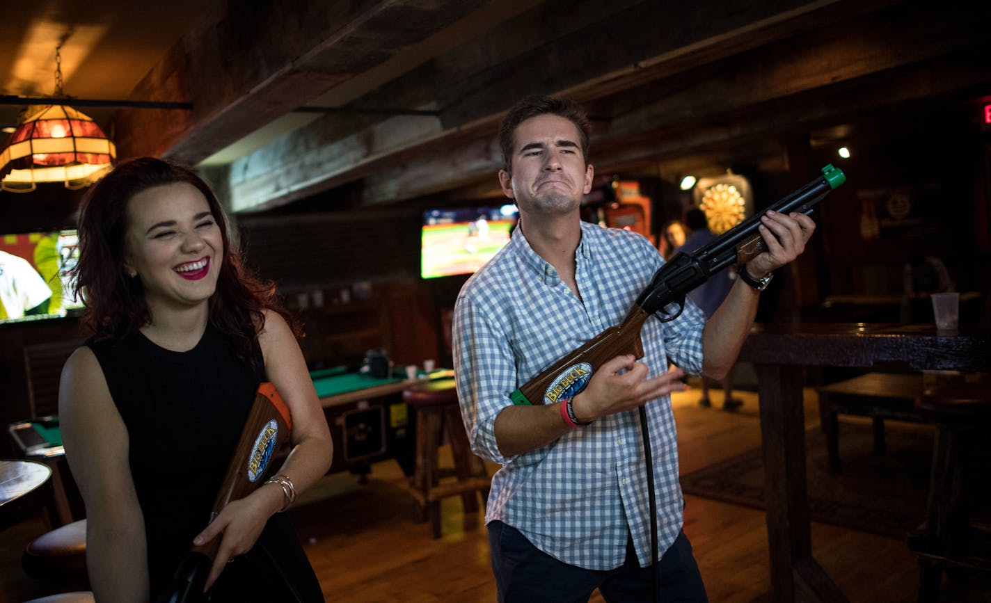 Star Tribune reporter Danielle Fox, left, laughed as Tinder Social date Zac Totten played the air guitar with a gun from the arcade game, Big Buck Hunter, early Sunday morning at Cowboy Jack's in downtown Minneapolis. ] (AARON LAVINSKY/STAR TRIBUNE) aaron.lavinsky@startribune.com Tinder has launched a feature that lets groups of friends match with other groups, an interesting navigation around "Minnesota Nice." Star Tribune features reporter Danielle Fox writes a first-person, experiential story