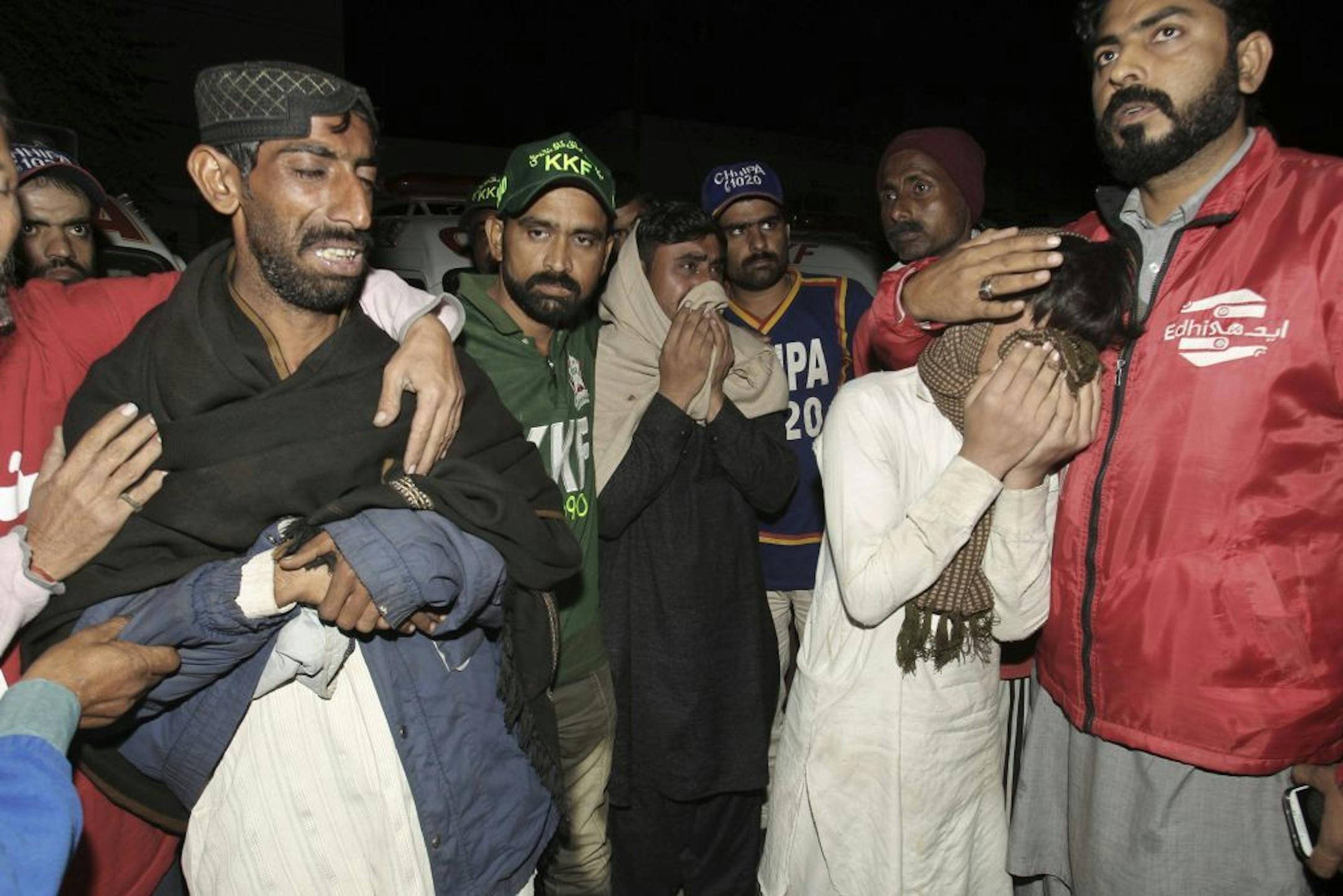 Pakistani relatives of bus accident victims mourn their death outside a hospital in Karachi, Pakistan, early Sunday, Jan. 11, 2015. Dozens of people were killed when a passenger bus collided with an oil tanker on a highway near Karachi.