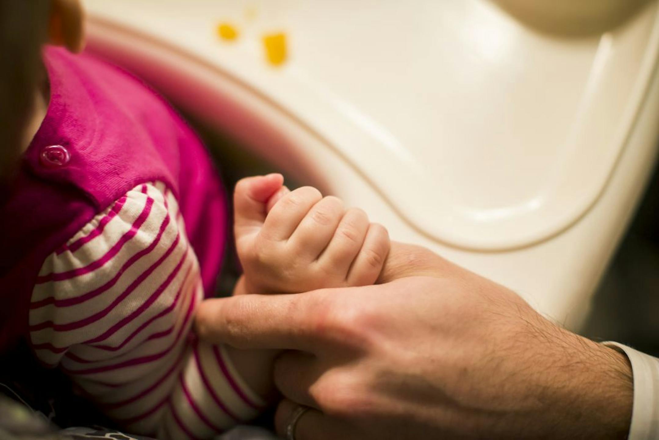 FILE -- A 10-month-old holds the thumb of her father Todd Bedrick, who took six weeks of paternity leave from his job, as he gets dinner for her at their home in Portland, Ore., Nov. 3, 2014. Large majorities of Americans say they support paid parental leave, yet legislation has never gone anywhere in Congress. Now could be different because for the first time, a Republican administration is backing it.