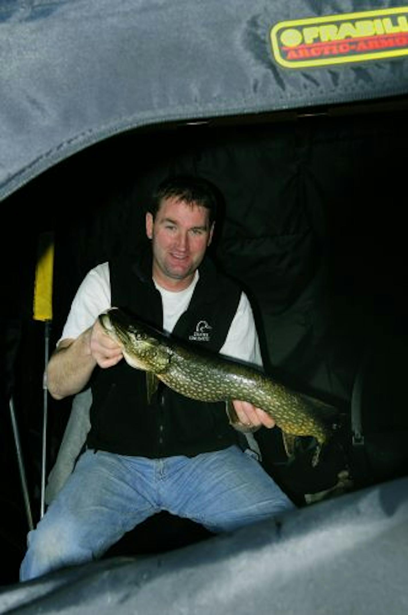 From inside a portable ice angling shelter Lindy Frasl of Fort Ripley displays a northern pike he hauled in while fishing for sunnies last week. The fish was released.