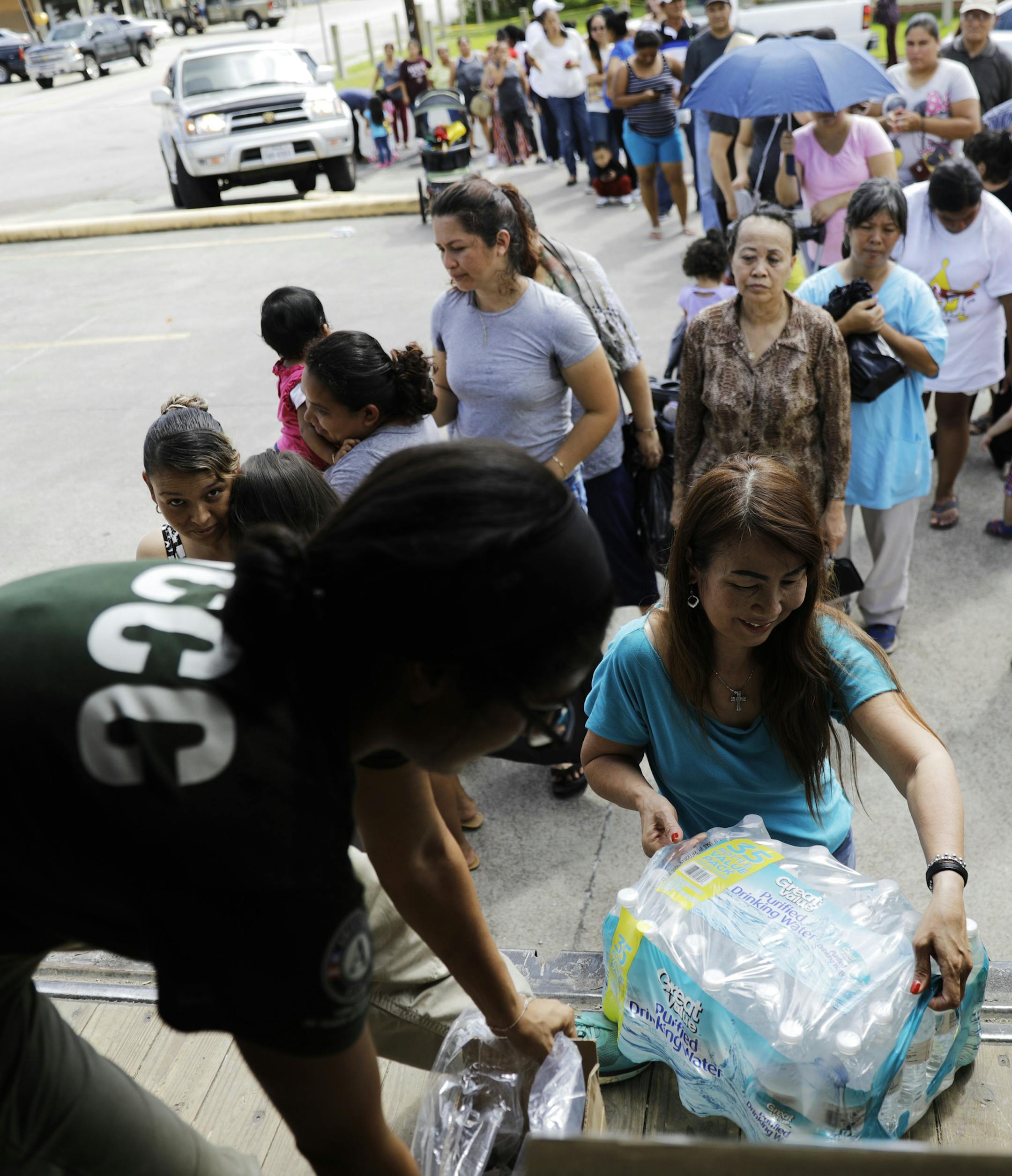 People stand on line for water, food and supplies at a distribution point in Port Arthur, Texas, Monday, Sept. 25, 2017. Jefferson County was drowned by more than 60 inches of rain during Hurricane Harvey, the most rainfall ever recorded in a single storm in the nation's history, according to preliminary data from the National Weather Service. (AP Photo/David Goldman)