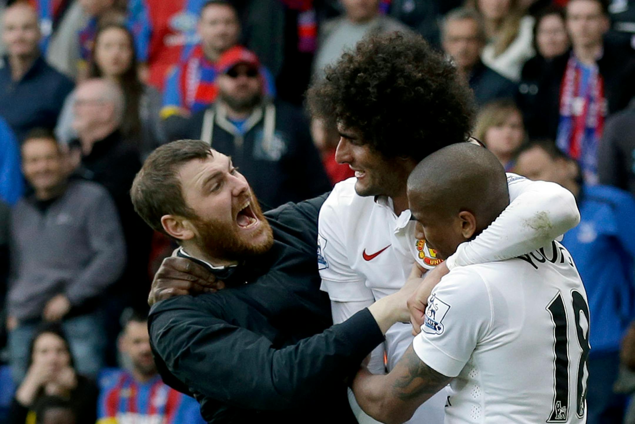 A Manchester United fan, left, joins in celebrations with Marouane Fellaini, second left, after he scored his side's second goal during the English Premier League soccer match between Crystal Palace and Manchester United at Selhurst Park stadium in London, Saturday, May 9, 2015.