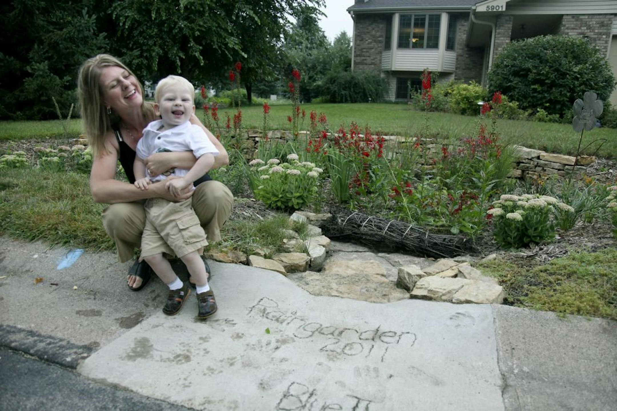 Dawn Pape's played with her son near her rain garden. This is a curb-cut rain garden to handle runoff from street.(ELIZABETH FLORES/STAR TRIBUNE) ELIZABETH FLORES � eflores@startribune.com
