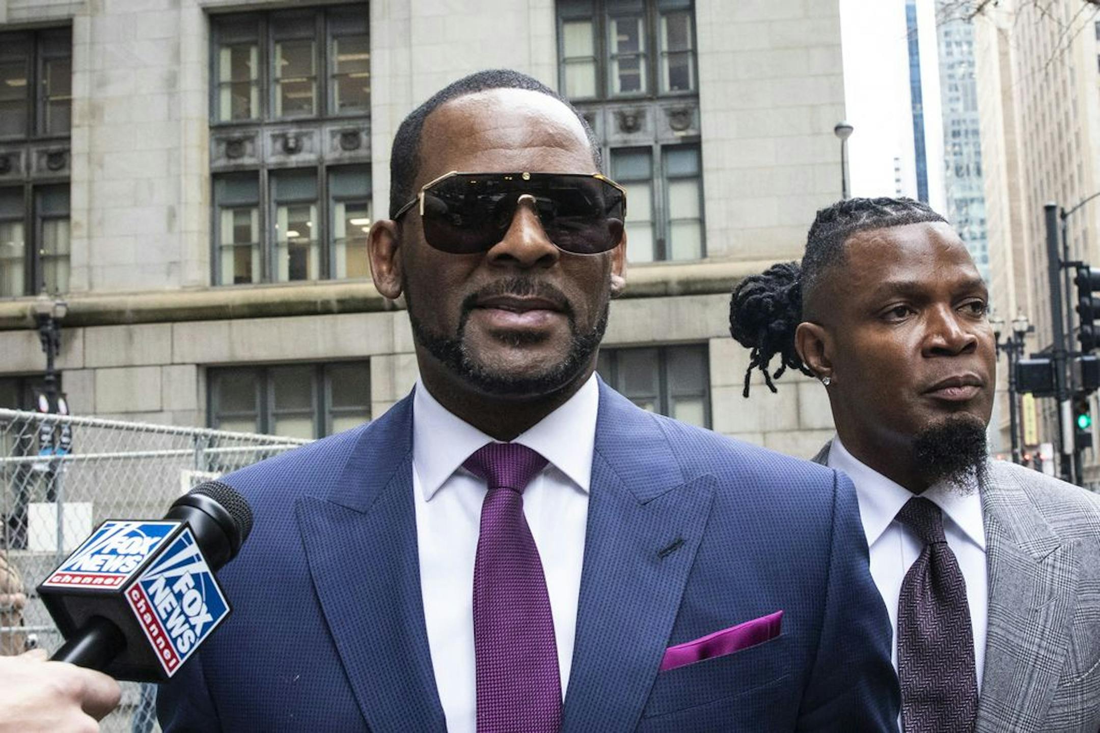 FILE - This March 13, 2019 file photo shows R. Kelly and his publicist Darryll Johnson, right, leaving The Daley Center after an appearance in court for Kelly's child support case in Chicago. Prosecutors in Chicago have charged Kelly with 11 new sex assault charges, some that are more serious than those first filed against him in February. The Chicago Sun-Times reported Thursday, May 30, on its website that the charges include counts that carry a potential sentence of up to 30 years in prison. T