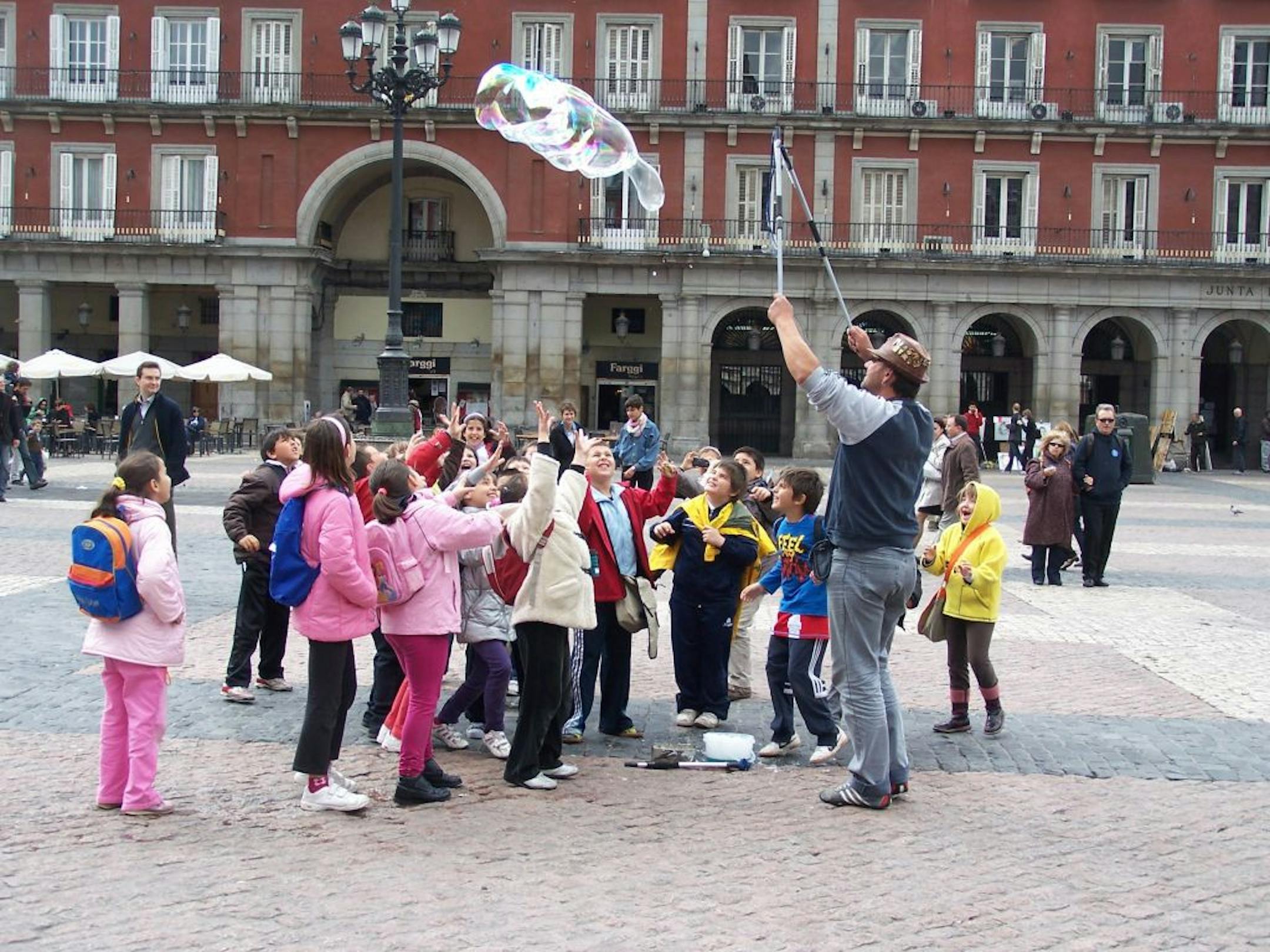 Children chase giant bubbles in the Plaza de Mayor in Madrid, Spain.