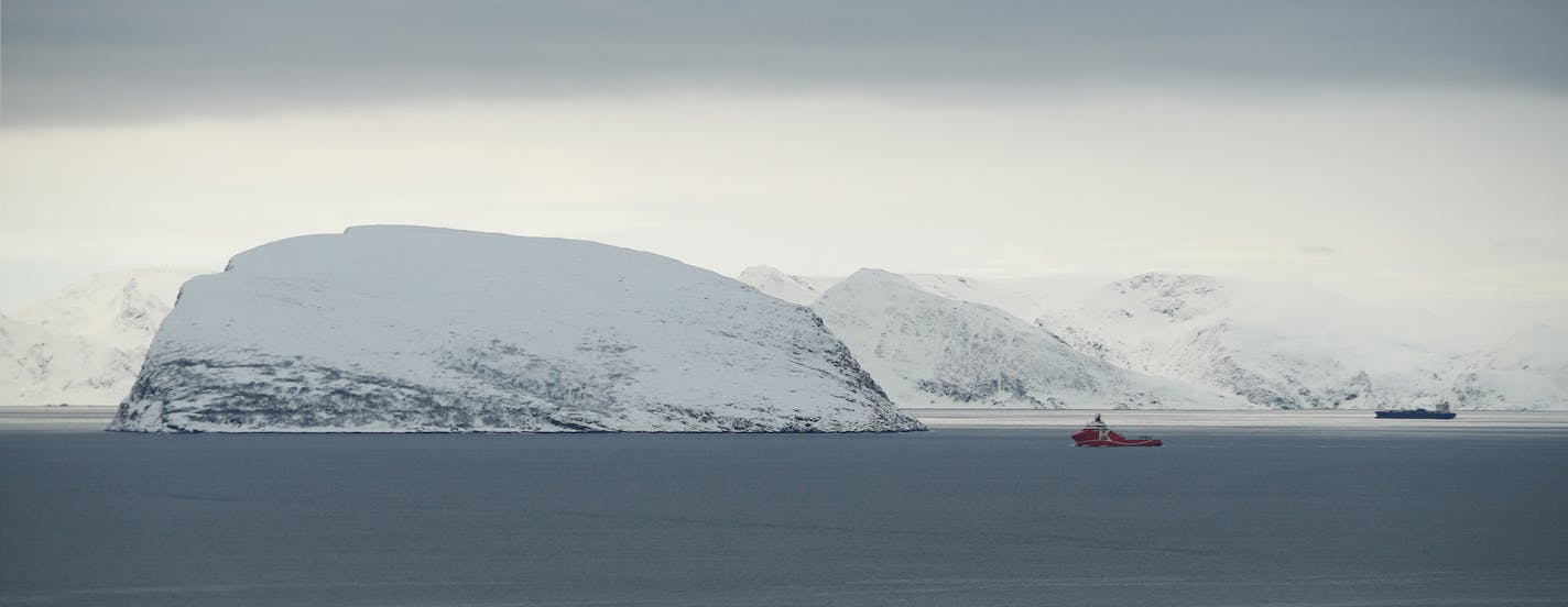 In this photo taken Thursday, Feb. 4, 2016, showing a view towards the refugee camp in Hammerfest, northern Norway, and an inlet from the Barents Sea. After hiding below the horizon for two long months, the sun has finally risen in Hammerfest, casting a pale pink hue over the Arctic landscape surrounding the world's northernmost refugee shelter. (AP Photo/Alastair Grant)