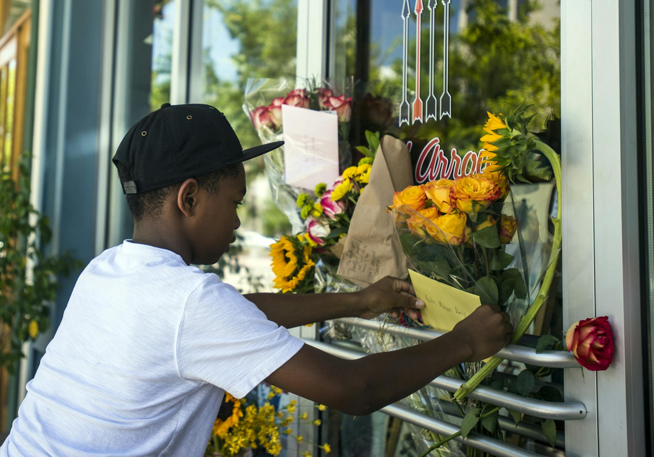 Mason Matthews, 10, leaves a card at a makeshift memorial for shooting victim Jillian Johnson at Red Arrow Workshop in River Ranch in Lafayette, La., Friday, July 24, 2015. According to The Daily Advertiser, store co-owner Johnson was among the victims that died following the Thursday night shooting at the Grand 16 theater. (Paul Kieu/The Daily Advertiser via AP)