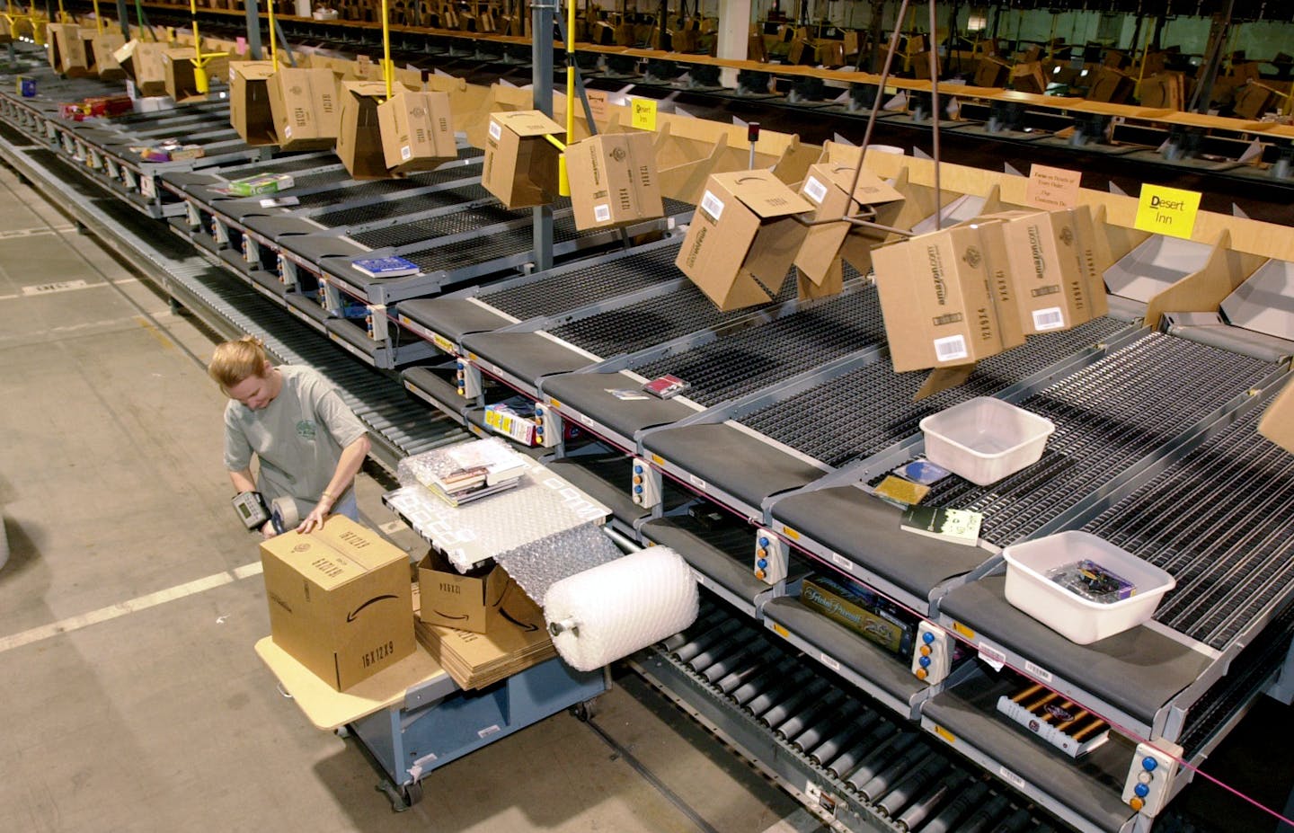 In this Nov. 13, 2002 photo, an Amazon employee packages an order to be shipped from its Coffeyville, Kan., warehouse. A Coffeyville Chamber of Commerce executive on Wednesday, Oct. 1, 2014, that the Seattle-based online retailer plans to close the facility in February, part of a move to have its distribution centers closer to the bulk of its customers. (AP Photo/The Wichita Eagle, Brian Corn)