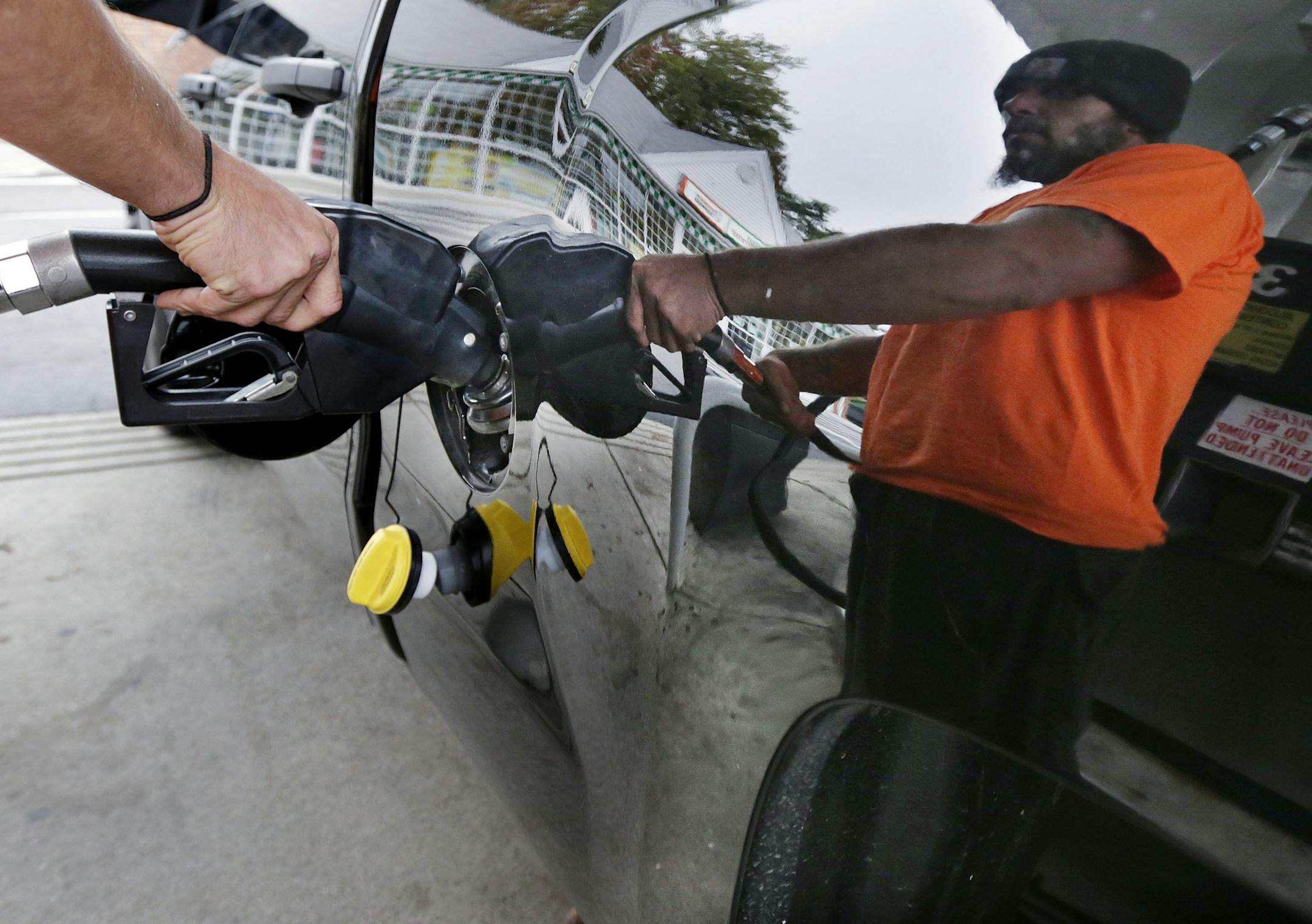 FILE - In this Sept. 30, 2014 file photo, Dana Ripley, of Winthrop, Mass., fills the gas tank of his truck at a service station in Andover, Mass. A swoon in the price of oil is lowering fuel bills for drivers, shippers and airlines, but it is not without downsides for both the U.S. oil boom and the broader economy. (AP Photo/Charles Krupa, File)