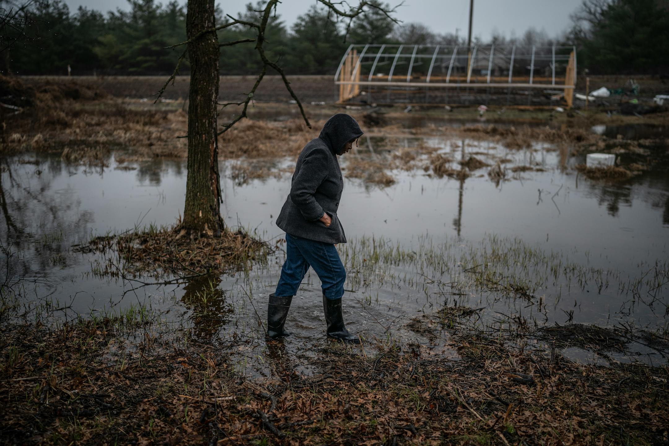 Jane Windsperger, owner of a 3.8 acre farm called GEDEF Farms, walks through water-logged land.