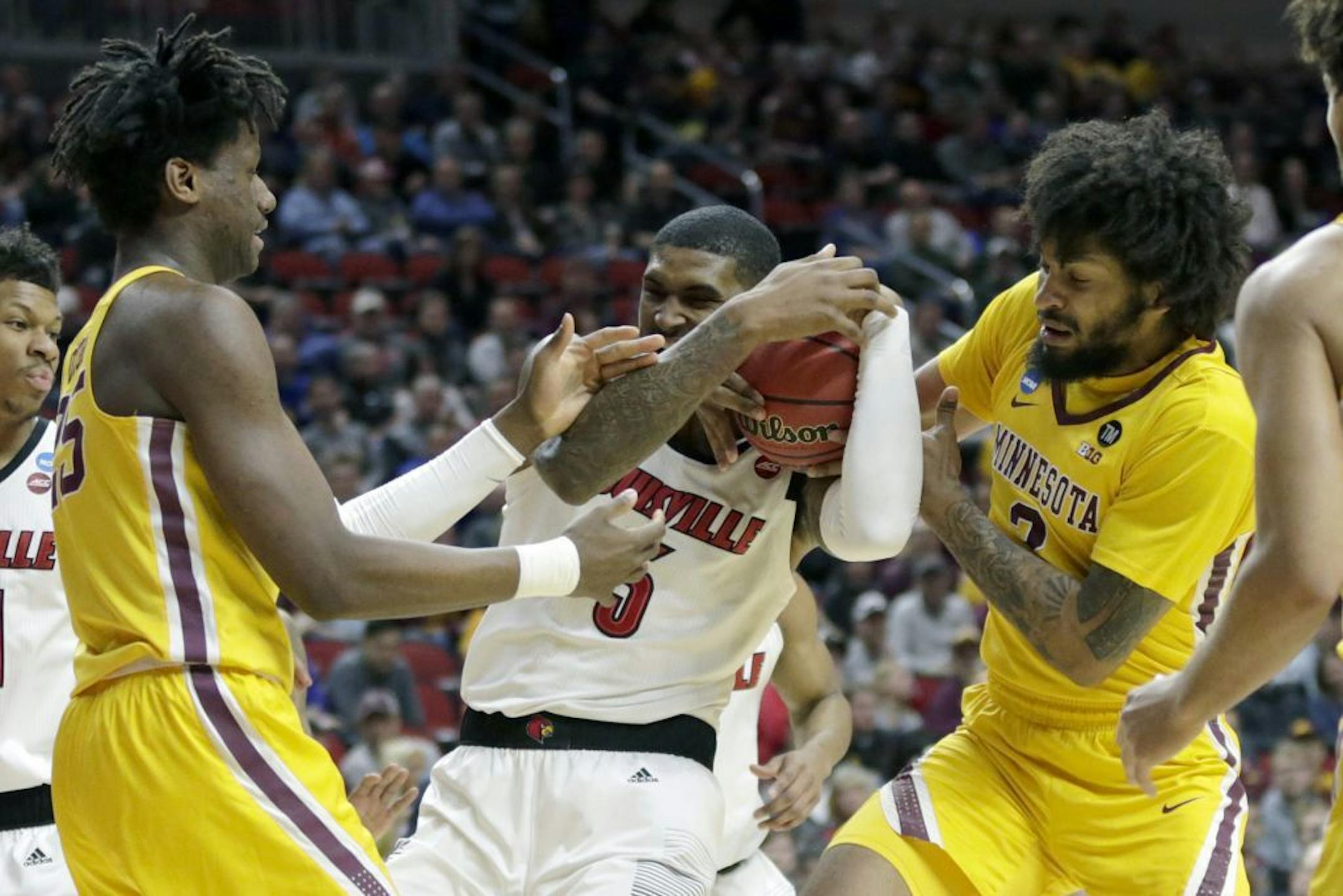 Minnesota's Daniel Oturu, left, and Jordan Murphy (3) struggle for the ball with Louisville's Malik Williams (5) during the first half of a first round men's college basketball game in the NCAA Tournament, in Des Moines, Iowa, Thursday, March 21, 2019.