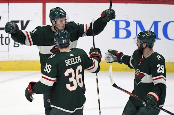 Minnesota Wild's Nick Seeler (36) and Greg Pateryn (29) congratulate Charlie Coyle on scoring against the Tampa Bay Lightning in the first period of a