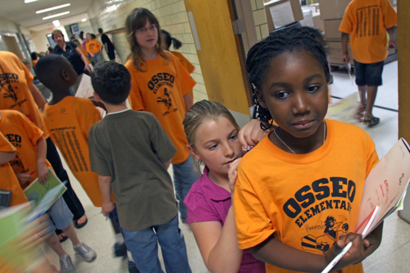 Osseo Elementary fifth-grader Maddie Miller signed second-grader Takyezia Lee's T-shirt during some free time after the final school assembly. Not only is it the last day of school at Osseo Elementary, the school is being closed, and staff and students are transferring to different schools next year.