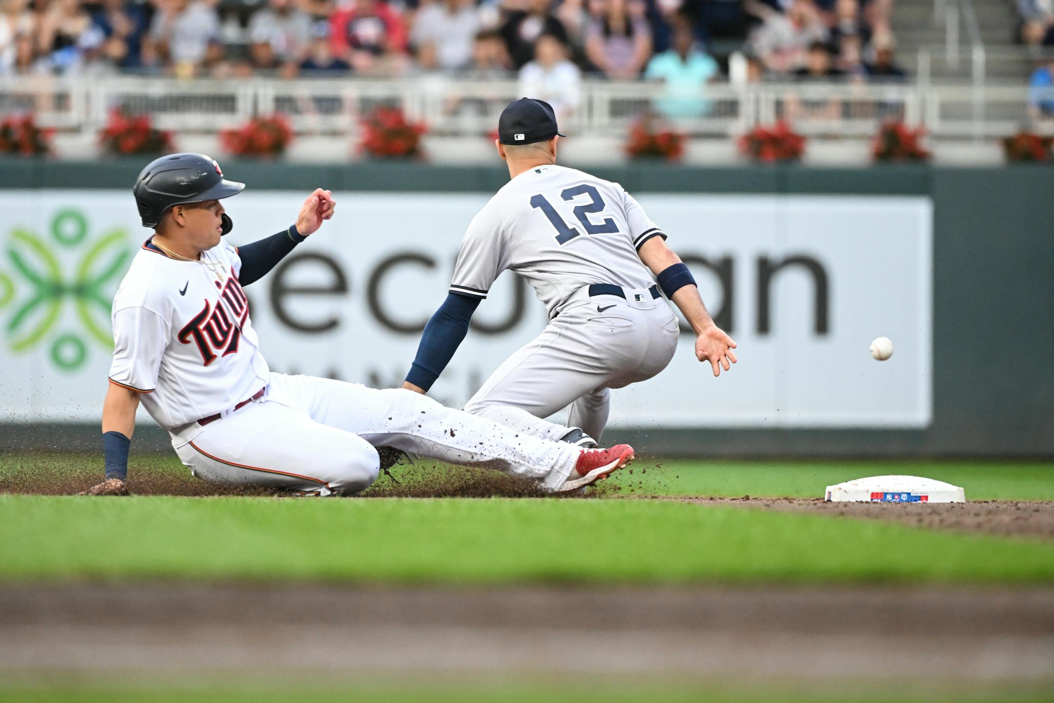 Minnesota Twins third baseman Gio Urshela (15) slides back to second as New York Yankees shortstop Isiah Kiner-Falefa (12) is unable to get the tag after a fly out hit by designated hitter Jose Miranda (64) in the bottom of the third inning. Urshela was ruled out after officials say he failed to tag third base on his way back to second.