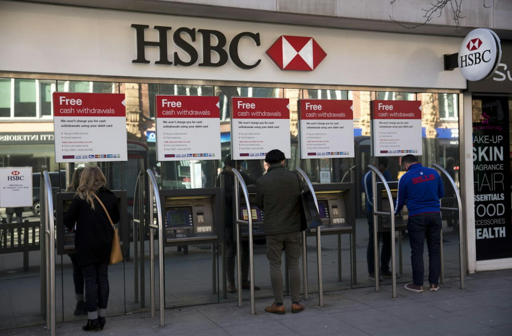 People use ATM machines outside a branch of HSBC in London, Wednesday, Feb. 18, 2015. The chief political commentator for The Daily Telegraph newspaper, Peter Oborne has resigned over the British newspaper's coverage of the HSBC scandal, alleging Wednesday it was part of an effort to downplay critical coverage of the bank to preserve lucrative advertising contracts. Oborne accused the newspaper of carrying out a form of "fraud on its readers" by burying coverage of leaks showing that the bank he