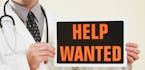 iStockphoto.com
A medical doctor holding a help wanted sign.