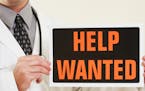 iStockphoto.com
A medical doctor holding a help wanted sign.