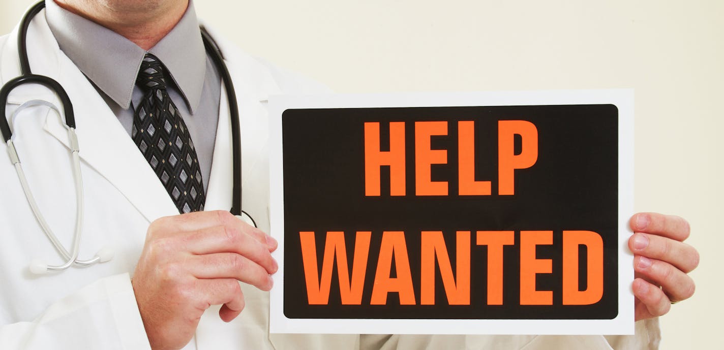 iStockphoto.com
A medical doctor holding a help wanted sign.