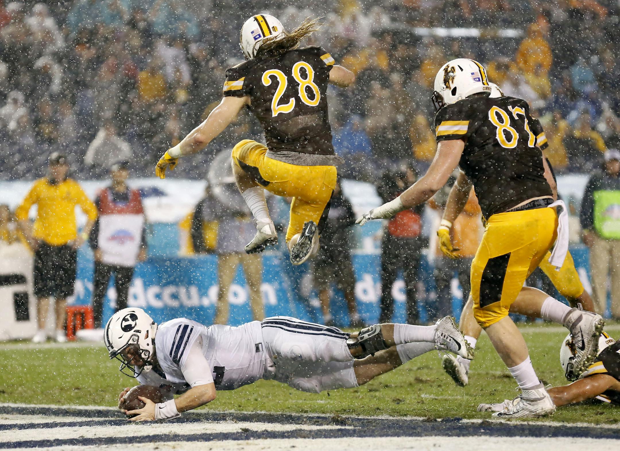 BYU quarterback Tanner Mangum, bottom, dives for a touchdown as Wyoming safety Andrew Wingard, top, leaps over him during the first half of the Poinsettia Bowl NCAA college football game Wednesday, Dec. 21, 2016, in San Diego. (AP Photo/Ryan Kang)