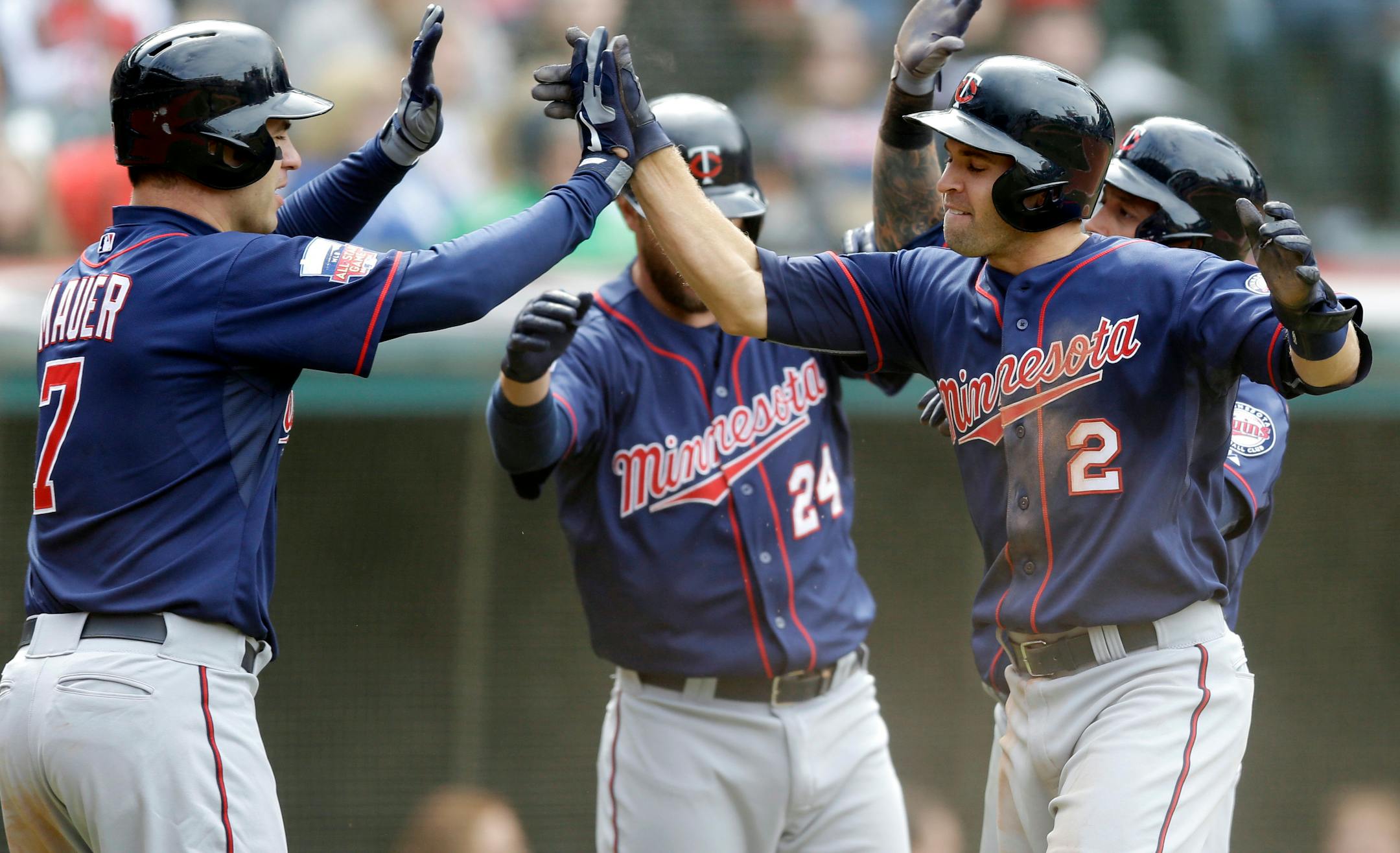 Minnesota's Joe Mauer (7) and Brian Dozier (2) celebrate after scoring on a three-run double from Chris Colabello off Cleveland's Blake Wood during the sixth inning Sunday. Twins' Jason Bartlett also scored.