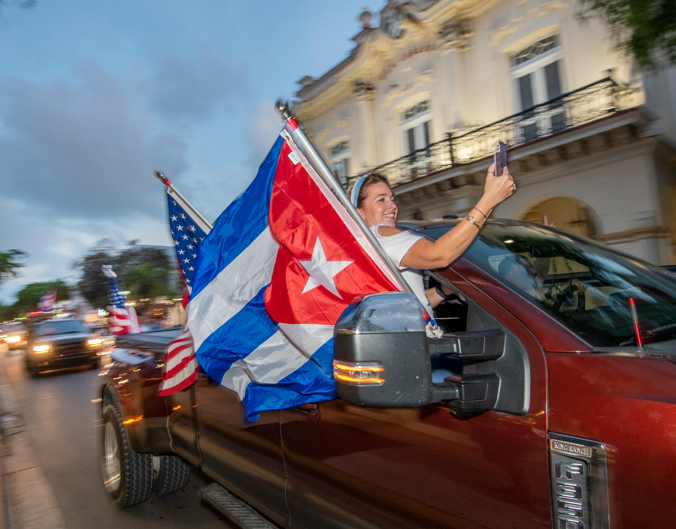 Members of the 'Gran Caravana,' (Big Caravan), pass the Cuba-centric San Carlos Institute on Duval Street Wednesday, July 14, 2021, in Key West, Fla., rallying support for the Cuban people. Roughly four dozen vehicles started the permitted parade 100 miles north in Key Largo, with more vehicles joining along U.S. 1, and ultimately connceting with dozens more in Key West for a parade on the island's main drag, Duval Street. (Rob O'Neal/The Key West Citizen via AP)
