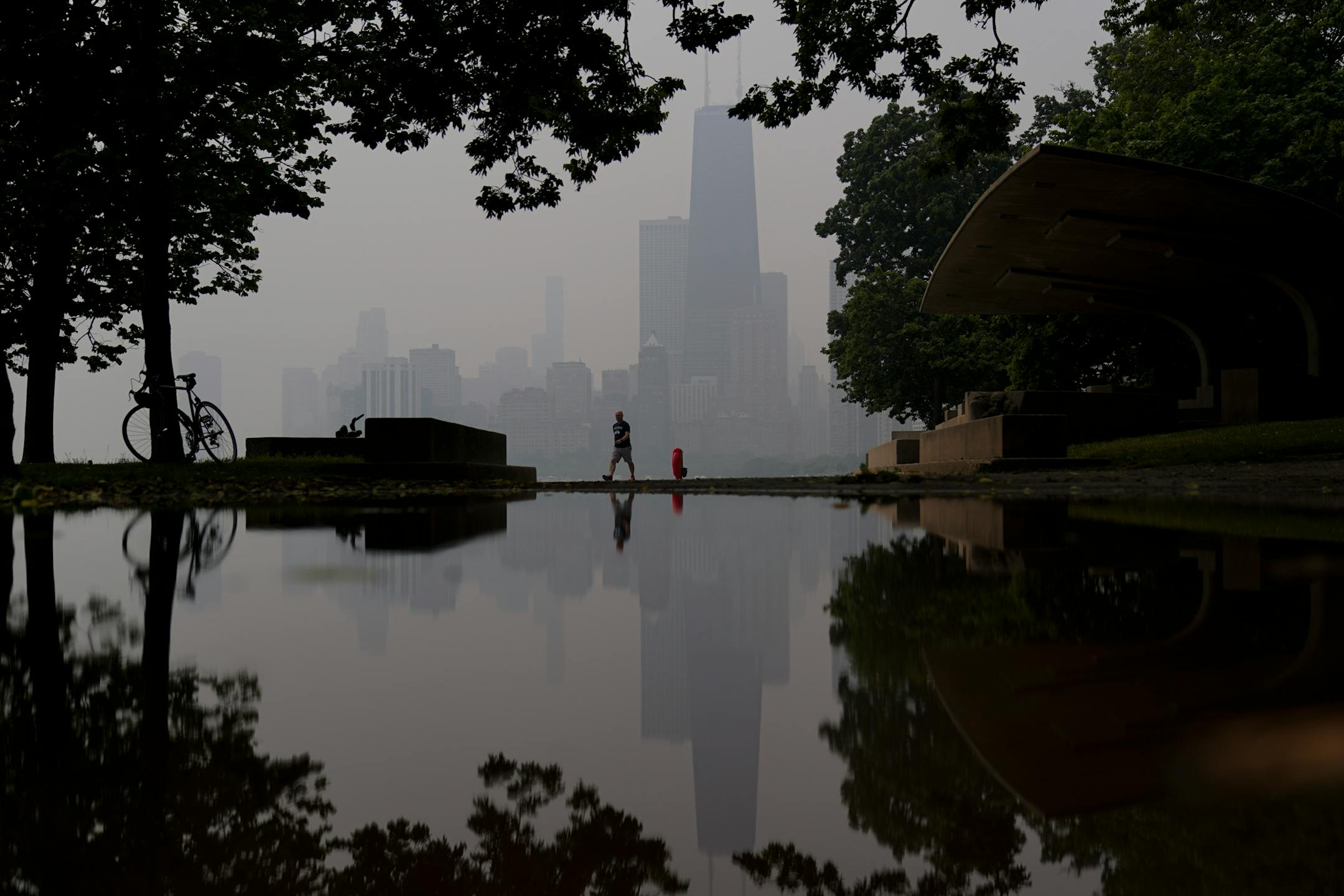 A person walks along the shore of Lake Michigan as the downtown skyline is blanketed in haze from Canadian wildfires in Chicago.