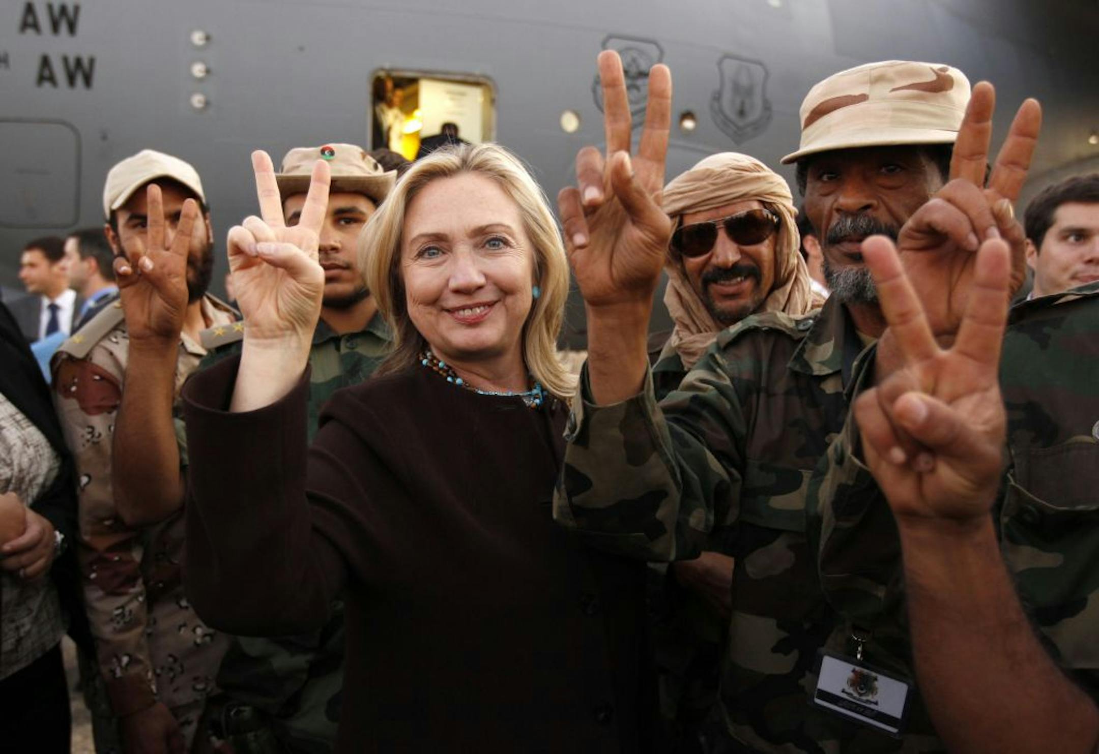U.S. Secretary of State Hillary Rodham Clinton gestures with Libyan soldiers upon her departure from Tripoli in Libya Tuesday, Oct.18, 2011.