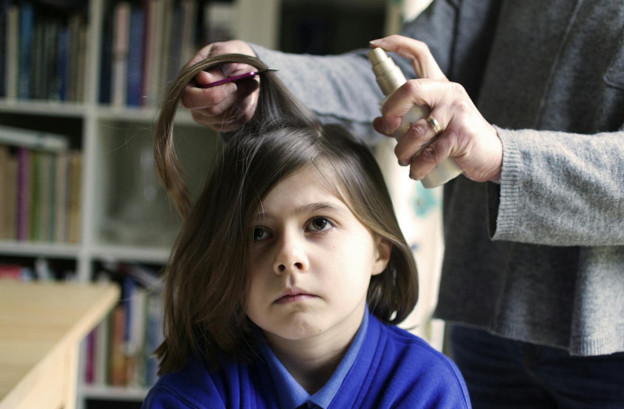 A young girl receives treatment for head lice.