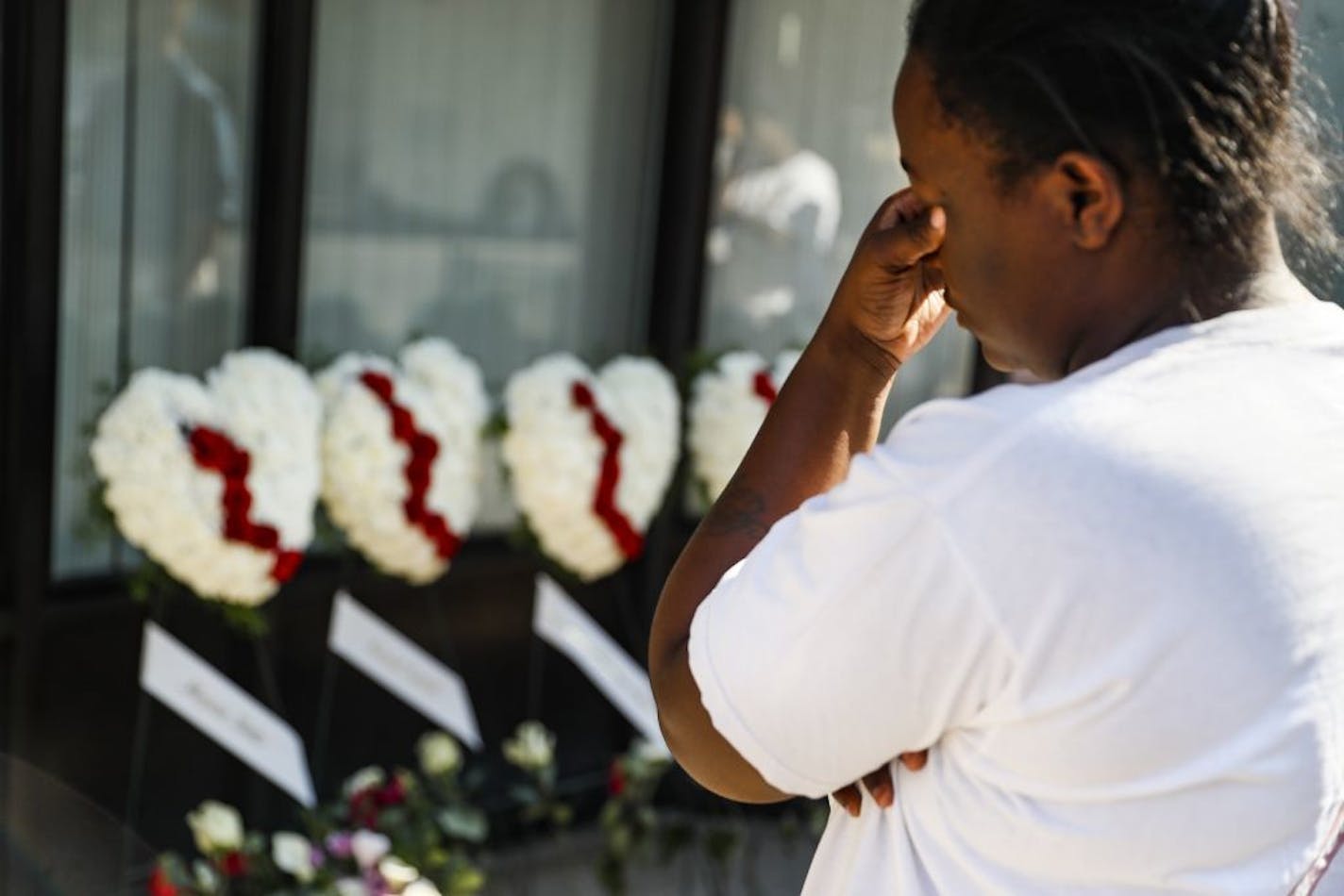 Finesse McNichols, sister of slain mass shooting victim Thomas "TJ" McNichols, mourns beside a memorial near the scene of the crime, Monday, Aug. 5, 2019, in Dayton, Ohio.