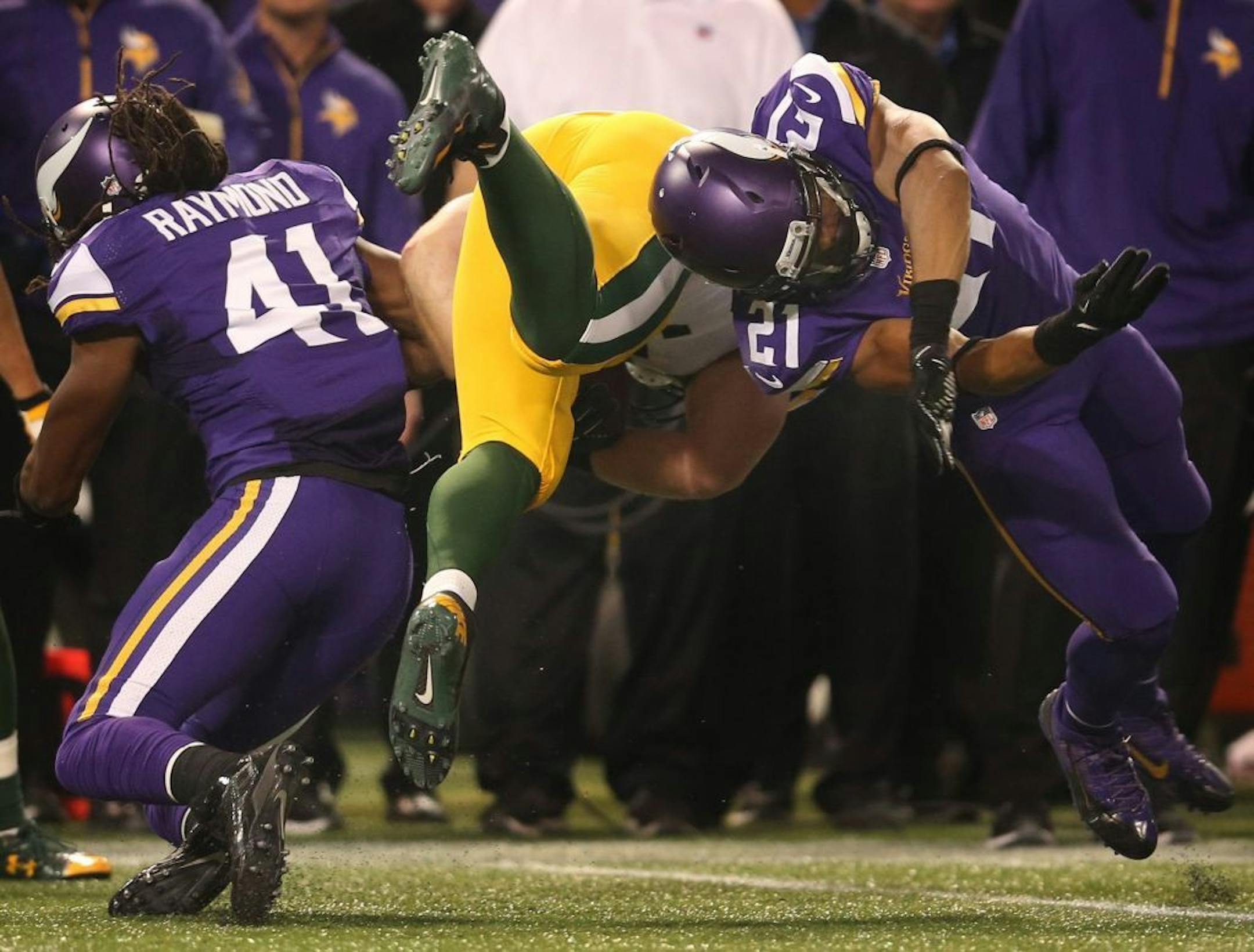 Minnesota Vikings cornerback Josh Robinson and Vikings safety Mistral Raymond tackle Green Bay Packers fullback John Kuhn on a 1-yard pass in the second quarter on Sunday, October 27, 2013, at Mall of America Field in Minneapolis, Minnesota.