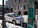 A parked car from Evie, an all-electric carshare service, next to an EV charging station near Union Depot in St. Paul.