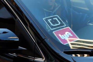 FILE - In this Tuesday, Jan. 12, 2016, file photo, a driver displaying Lyft and Uber stickers on his front windshield drops off a customer in downtown