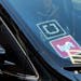 FILE - In this Tuesday, Jan. 12, 2016, file photo, a driver displaying Lyft and Uber stickers on his front windshield drops off a customer in downtown