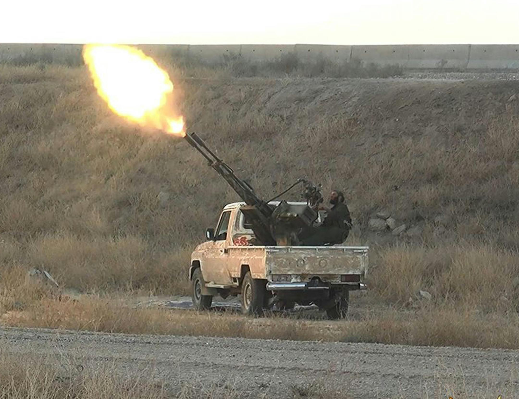 In this photo released on June 26, 2015, by a website of Islamic State militants, an Islamic State militant fires an anti-aircraft gun from the back of a pickup truck in Hassakeh city, northeast Syria. Since US-led airstrikes in Syria and Iraq have made it more difficult for the group’s forces to advance, IS has lost ground. (Militant website via AP)
