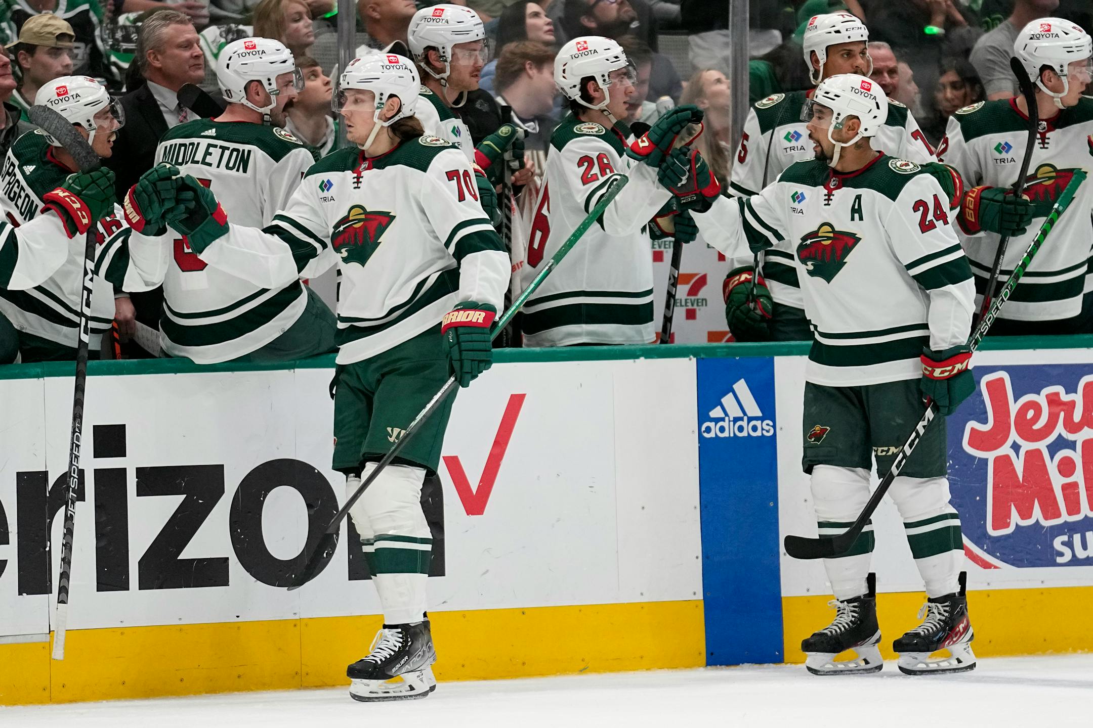 Minnesota Wild center Oskar Sundqvist (70) and Matt Dumba (24) celebrate with the bench after Sundqvist scored against the Dallas Stars in the first period of Game 2 .