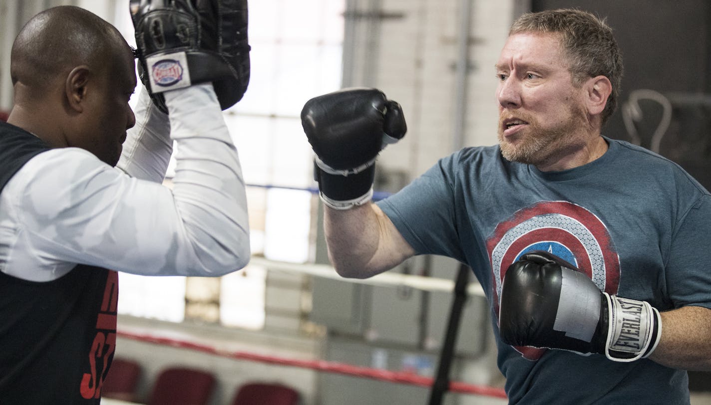 Carl Luepker, right, works out at Uppercut Boxing Gym with trainer Seko Tongola. ] (Leila Navidi/Star Tribune) leila.navidi@startribune.com BACKGROUND INFORMATION: Carl Luepker works out at Uppercut Boxing Gym with trainer Seko Tongola in Minneapolis on Tuesday, October 25, 2016. Carl Luepker has a rare neurological disorder (dystonia) that makes it hard for him to walk, write and speak clearly. He recently agreed to undergo an experimental surgery, known as "deep brain stimulation" at the Unive