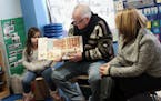 Gov. Tim Walz, top, reads a book to children at People Helping People, a shelter for families experiencing homelessness amid extreme cold weather cond