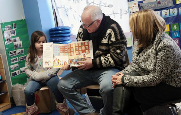 Gov. Tim Walz, top, reads a book to children at People Helping People, a shelter for families experiencing homelessness amid extreme cold weather cond