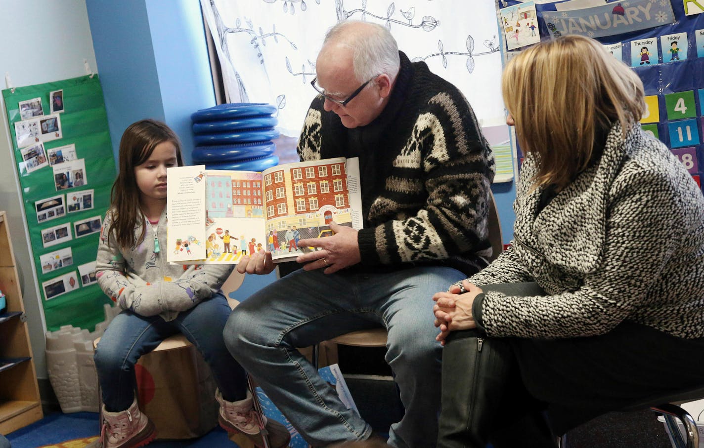 Gov. Tim Walz, top, reads a book to children at People Helping People, a shelter for families experiencing homelessness amid extreme cold weather conditions in Minnesota Tuesday, Jan. 29, 2019, in Minneapolis, accompanied by Lt. Gov. Peggy Flanagan, right. (AP Photo/Jim Mone)