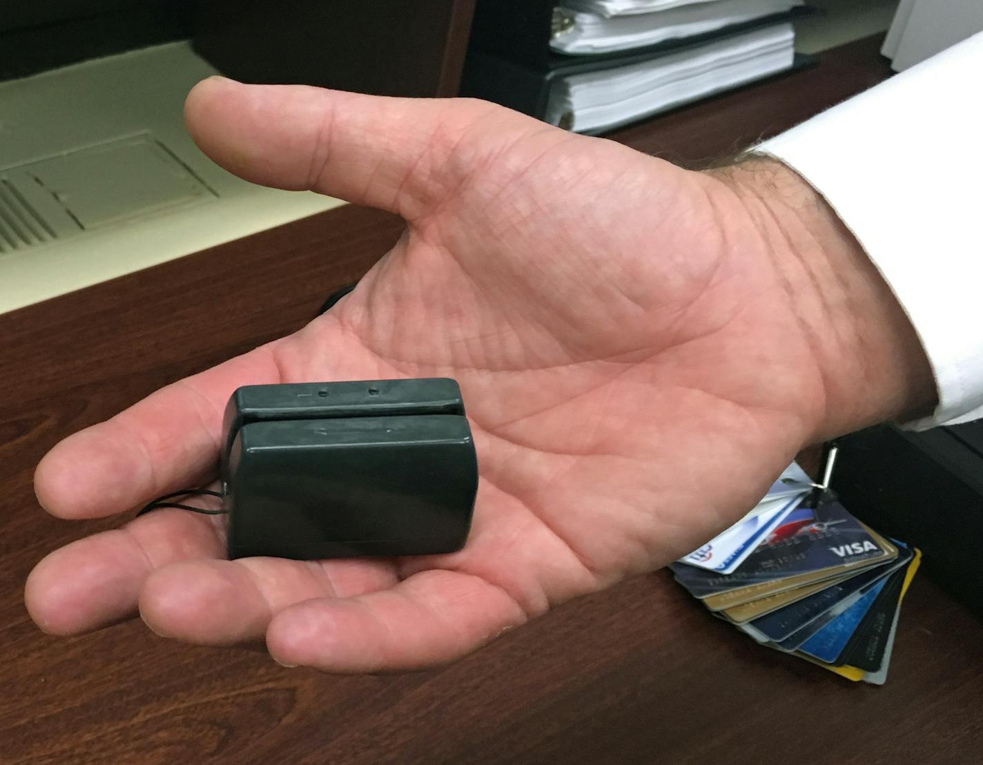 In this Dec. 17, 2015 photo, a New York City Police detective holds a credit card skimmer that was used by a street gang to copy metadata from legitimate credit cards for use in the manufacture of counterfeit cards and possibly identity theft. A new trend is emerging that shows street crews and local gangs giving up more traditional activities like gun point robberies or drug running for more white-collar varieties of crime like identity theft or credit card fraud. (AP Photo/Colleen Long)