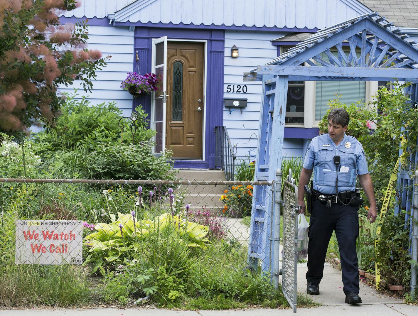 A Minneapolis Police officer walks outside of the site of a possible home invasion and homicide at 5120 DuPont Avenue North in Minneapolis on Thursday, July 16, 2015. ] LEILA NAVIDI leila.navidi@startribune.com /