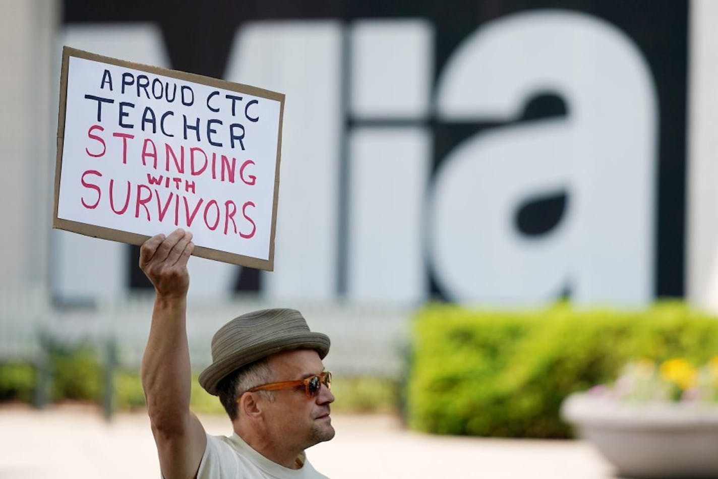 Andrew Erskine Wheeler, an acting instructor on staff at the Children's Theatre Company, held a sign as he stood in support of survivors during a protest in June.