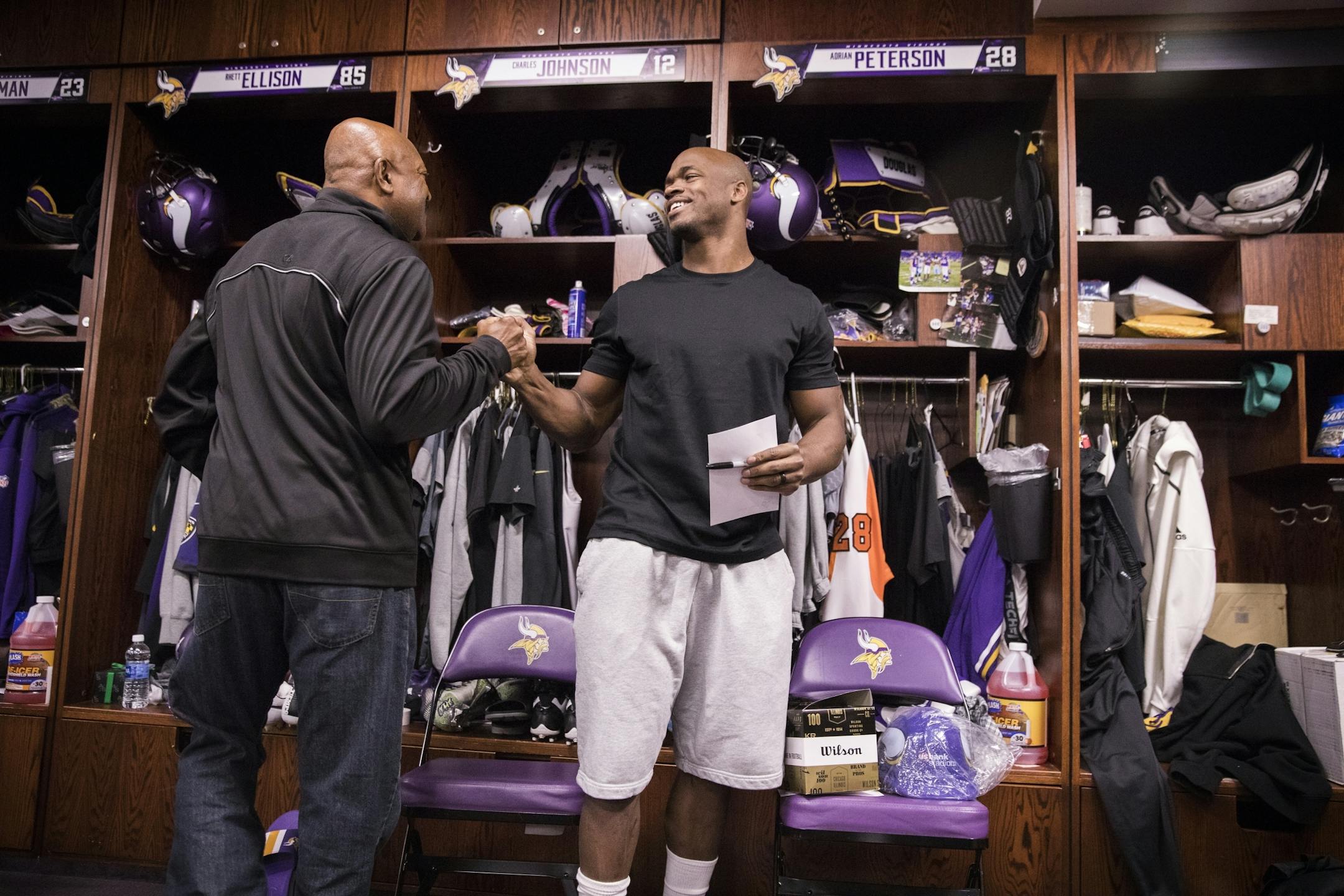 Adrian Peterson, right, says hello to former Viking Greg Coleman at his locker.
