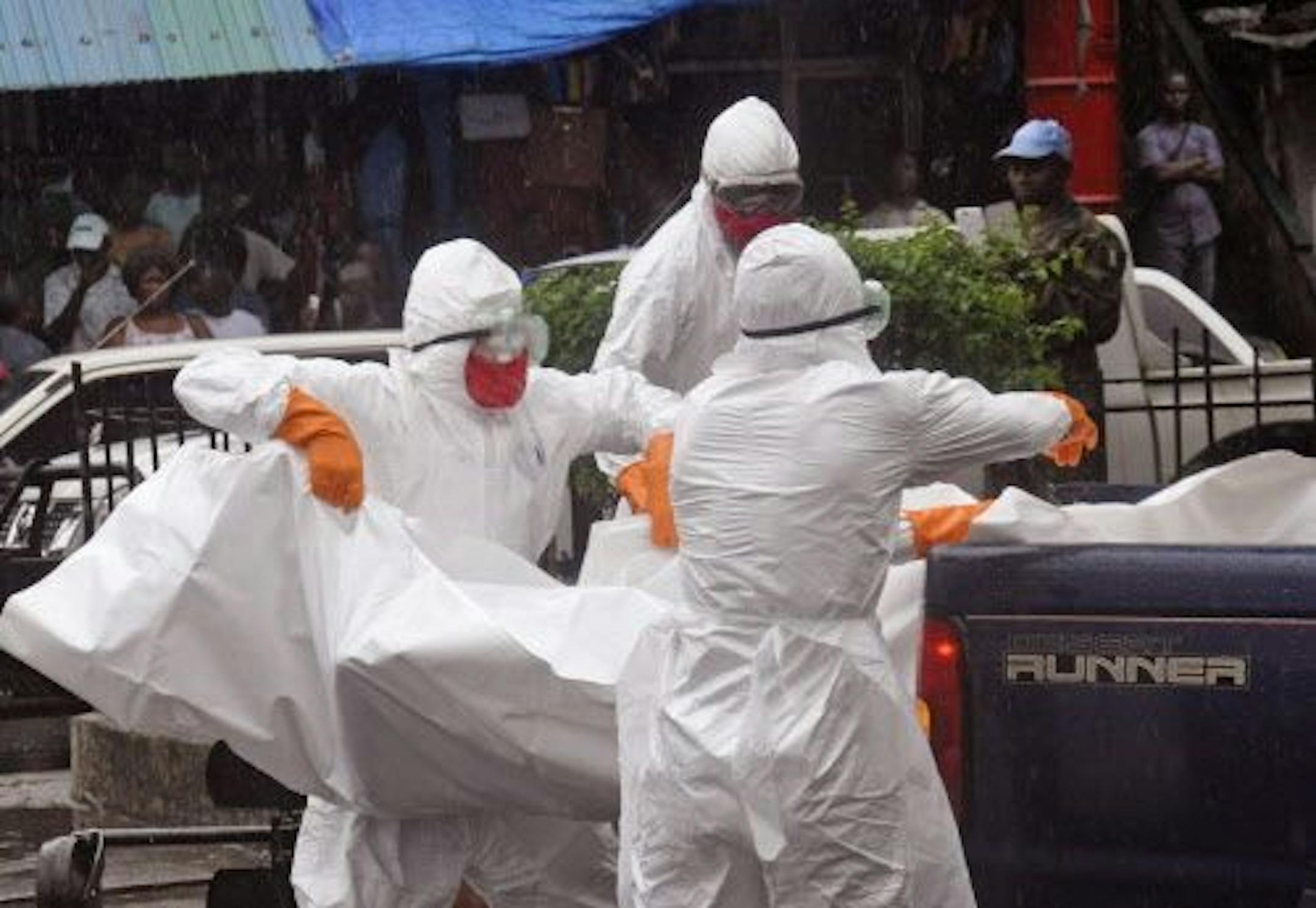Health workers load the body of person suspected of dying from the Ebola virus onto the back of a truck, in a busy street in Monrovia, Liberia, Tuesday, Sept. 2, 2014.