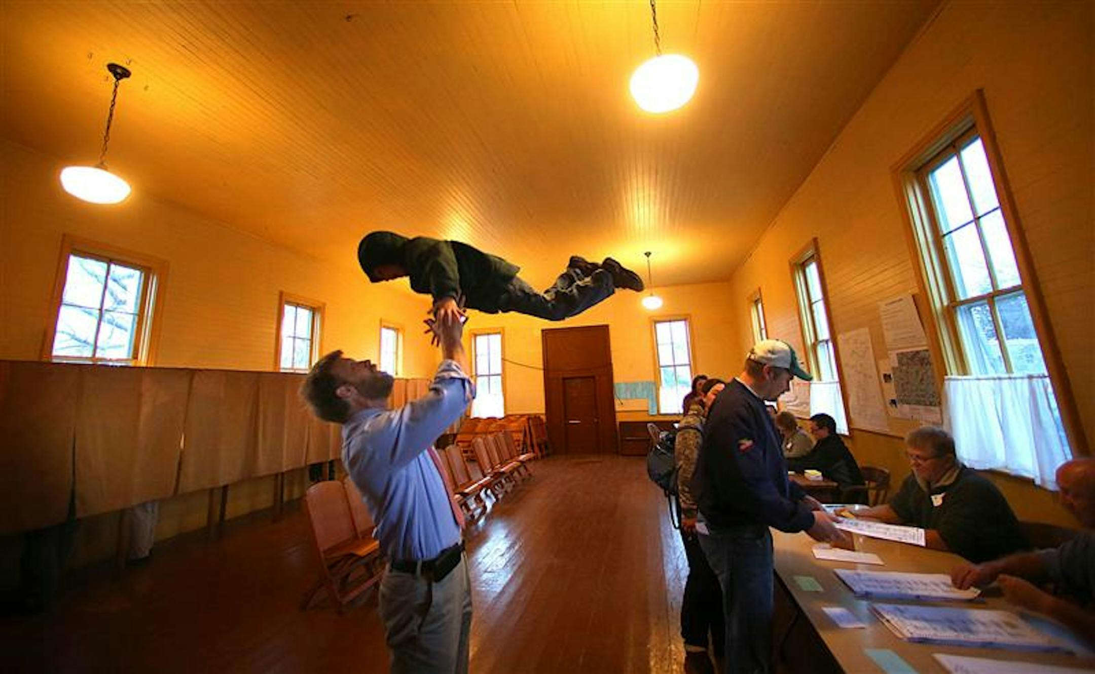 THIS RACE MUST BE A TOSSUP: Michael Delk played with his son, Noah, 4, while Noah's mother, Kris, finished voting at the Vasa Town Hall in Welch, Minn.