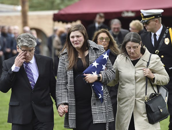 Andrea Parise, center, widow of corrections officer Joseph Parise, leaves his graveside services at Fairview Cemetery in Stillwater, Minn., on Tuesday