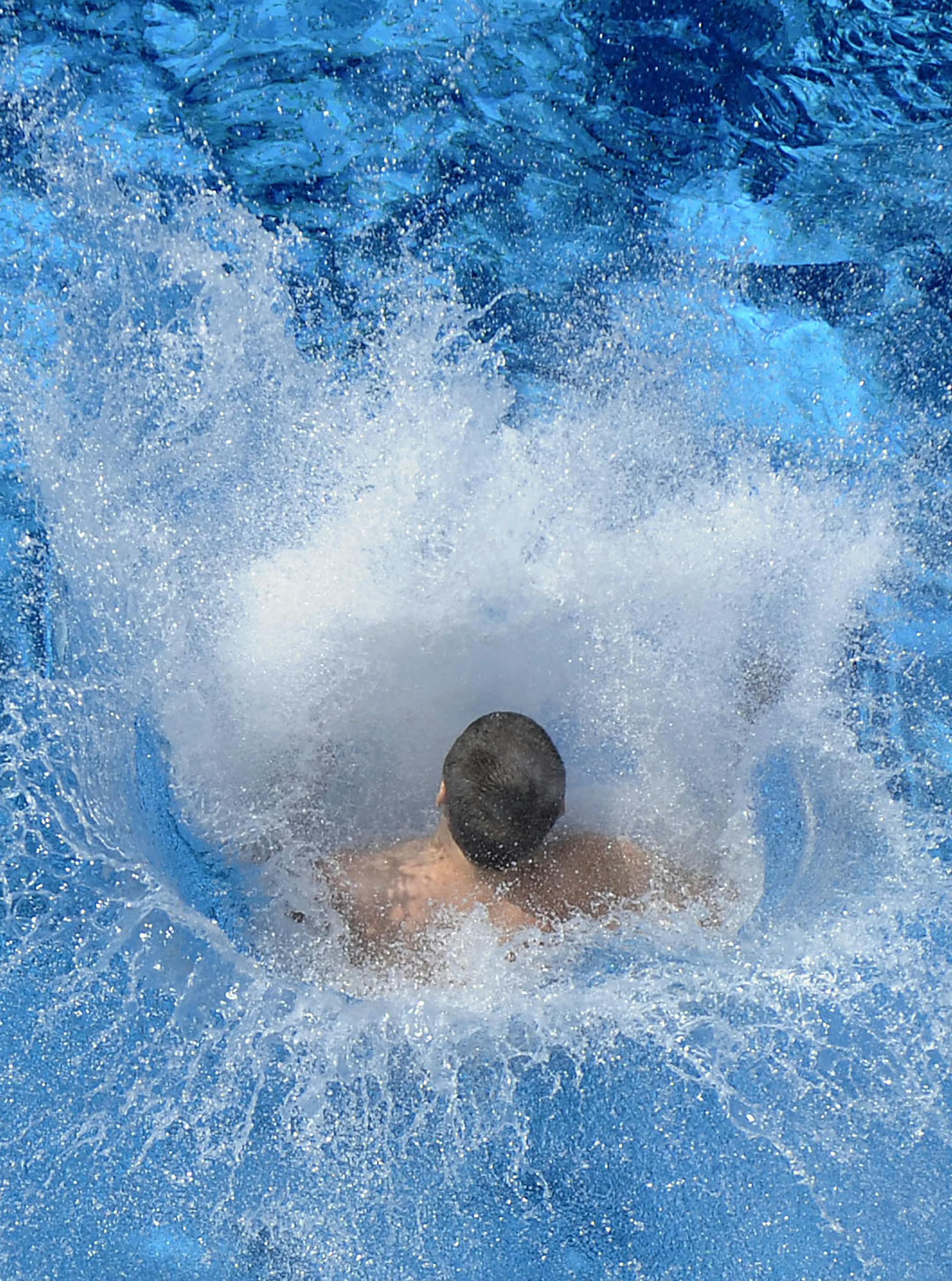 Water splashes as a teenager jumps into a public pool in Essen, western Germany, Wednesday June 24, 2009. (AP Photo/Mark Keppler)