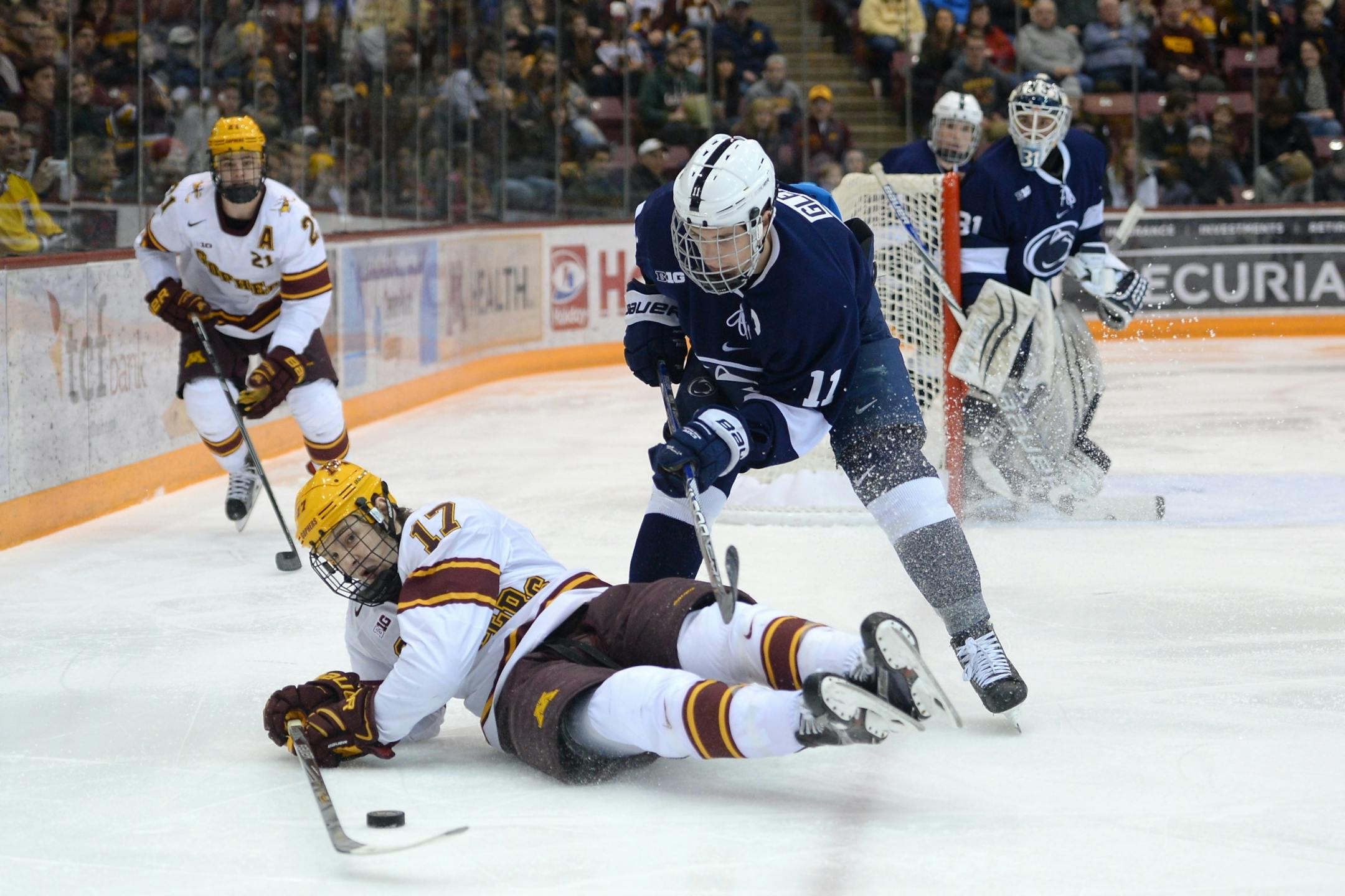 Minnesota Golden Gophers center Tommy Novak (17) tried to control the puck as he fell to the ice while being defended by Penn State Nittany Lions forward David Glen (11) in the second period.
