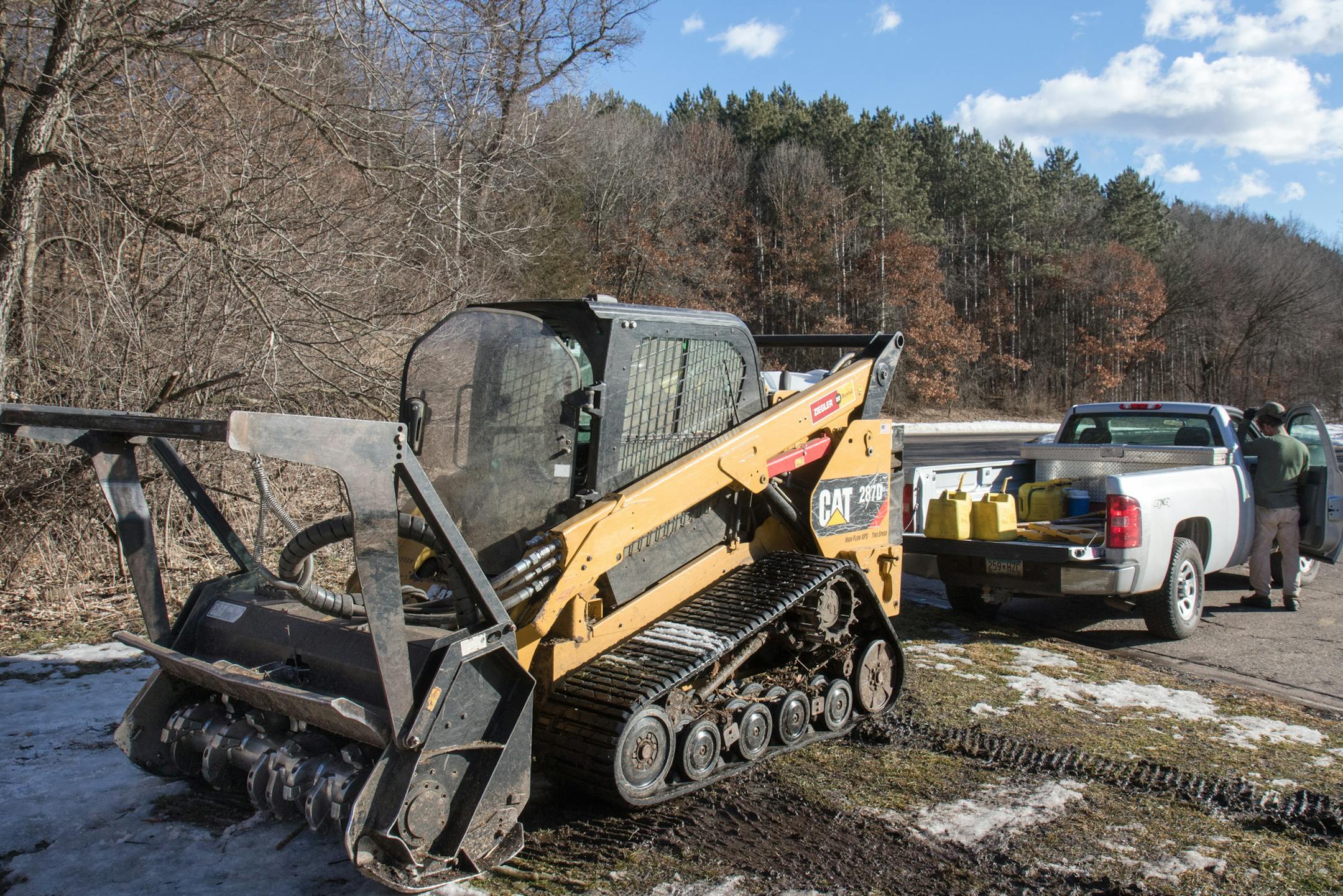 Tyler Tretbar from Prairie Restorations prepares to refuel a rented tracked vehicle with an attached wood chipper used to clear overgrown underbrush and invasive species at Cottage Grove Ravine Park.